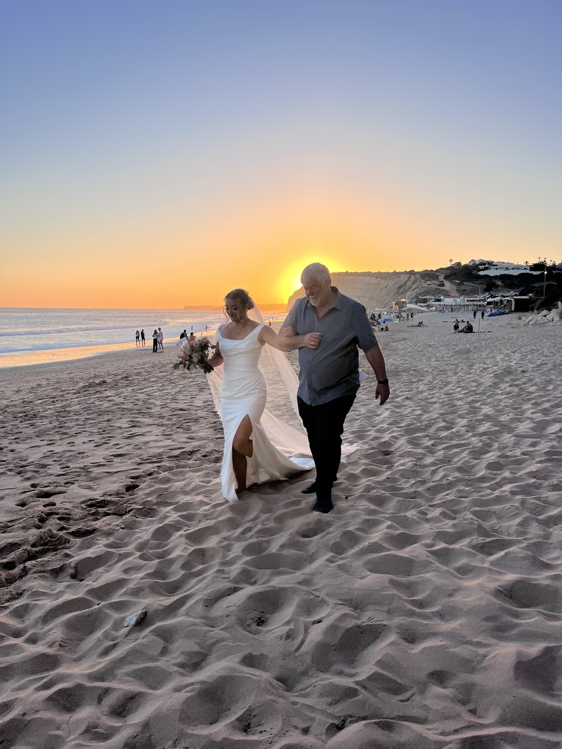 Bride walking onto a beach at sunset