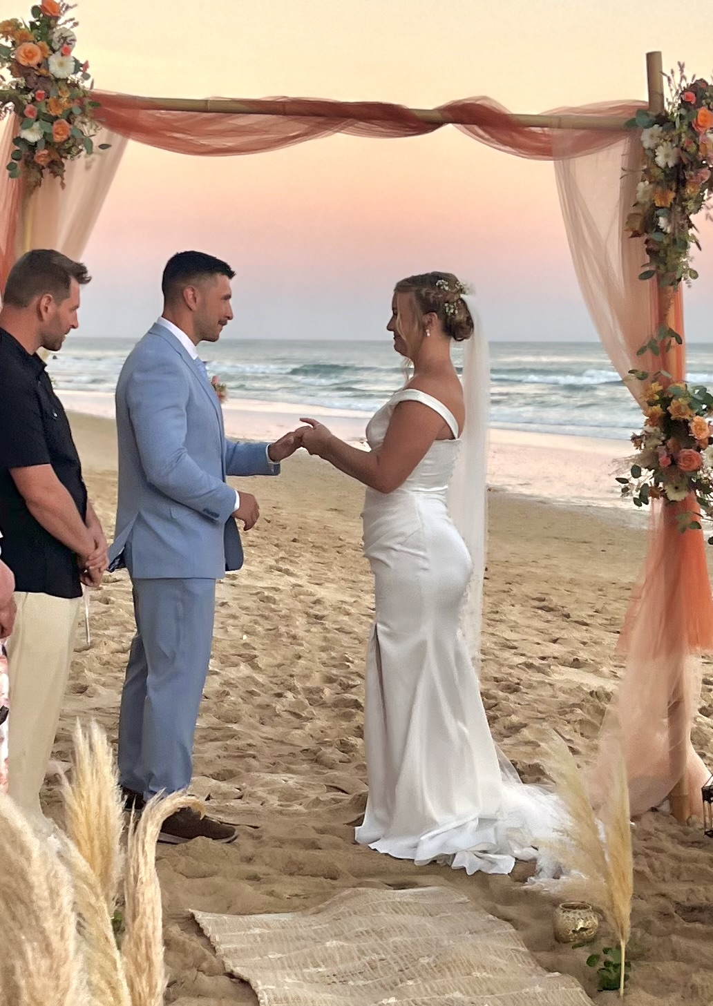 Couple at their ceremony under a flowered arch